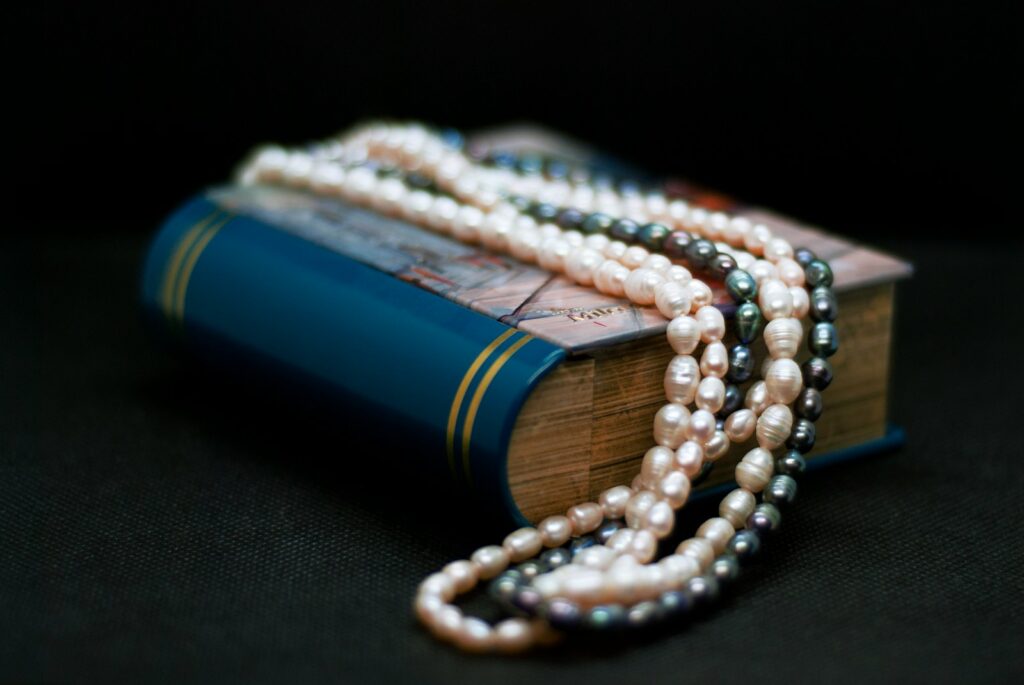 A book with a strand of pearls on top of it